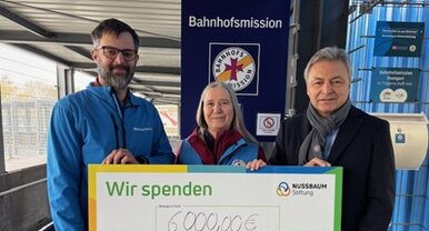 Peter Jahn (rechts) von der NUSSBAUM Stiftung überreicht einen Spendenscheck über 6.000 Euro an Antje Weber von der Bahnhofsmission Stuttgart und Jürgen Herrmann (links), stellvertretender Leiter der Stuttgarter Bahnhofsmission . | © Foto: Bahnhofsmission Stuttgart Scheckübergabe von NUSSBAUM an die Bahnhofsmission Stuttgart. | © Foto: Bahnhofsmission Stuttgart
