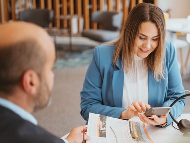 Beratungsgespräch zur Anzeigenschaltung mit Blick auf Printprodukt.